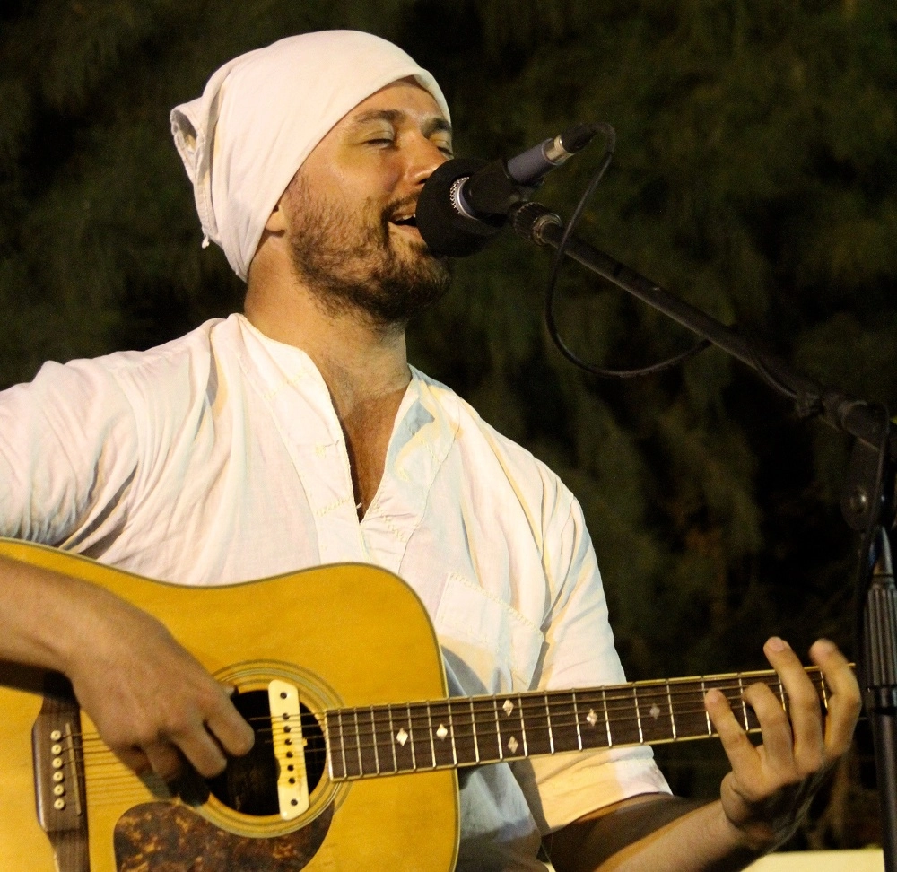 Greig Jahtoe singing and playing guitar at a microphone